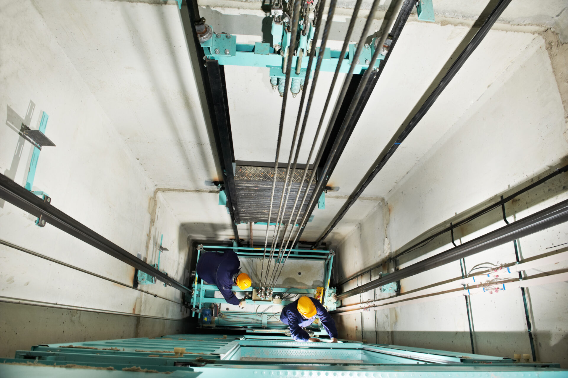 Two elevator technicians working in an elevator shaft, examining and making renovations.
